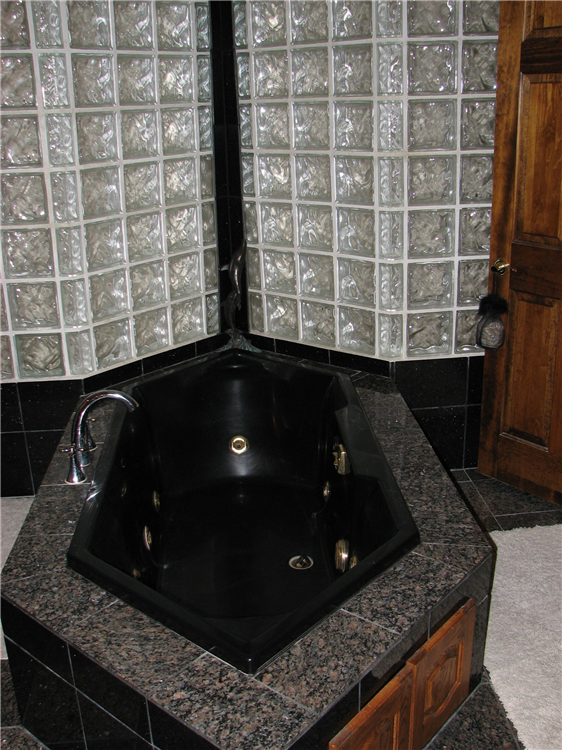 A Custom Jetted Tub Seated in Granite and Pushed Back into a Glass Block Light Shaft